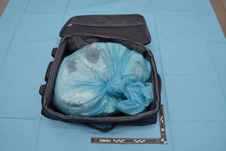 Geopende koffer met daarin een dichtgeknoopte blauwe zak